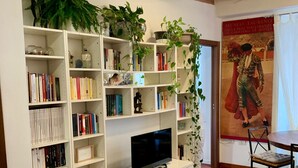 Un salon comprenant un meuble de rangement blanc pour l’équipement audiovisuel, un téléviseur à écran plat, une table basse en bois et un coin repas avec une table et des chaises.