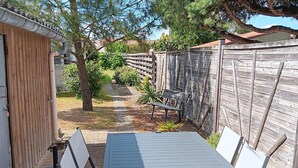 Un patio con tavolo e sedie, una recinzione in legno e un vialetto che conduce a un edificio.