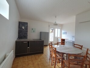 A kitchen with a dining table and chairs, a refrigerator, and a window with a view.