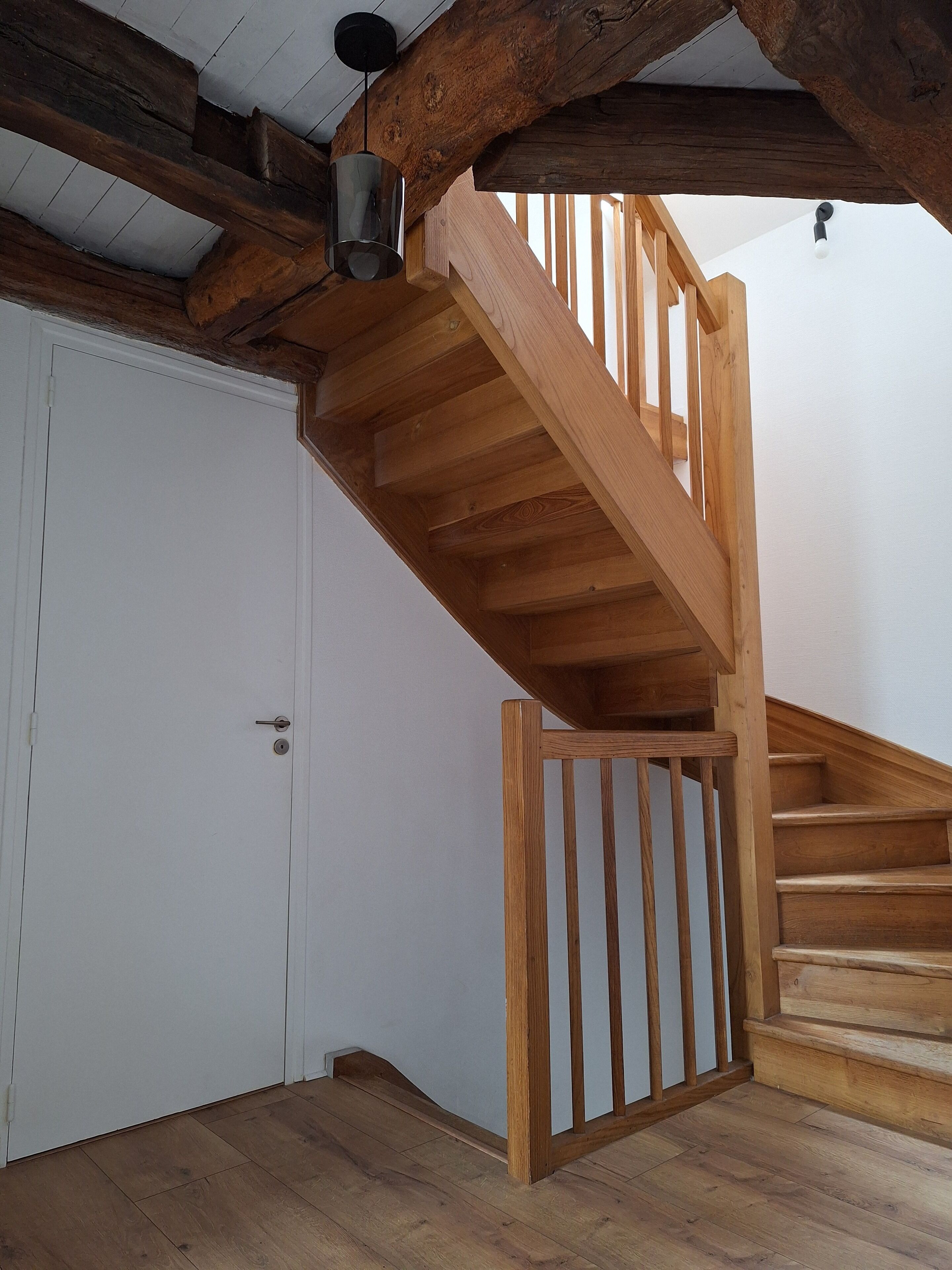 Eine Holztreppe mit Handlauf, die zu einer oberen Etage führt.