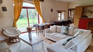A living room with a sofa, a dining table, and a kitchen area.