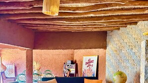 Una sala de estar acogedora con techo de madera, un sofá azul, una mesa de centro de madera con piezas de ajedrez y un globo terráqueo en una mesita auxiliar.