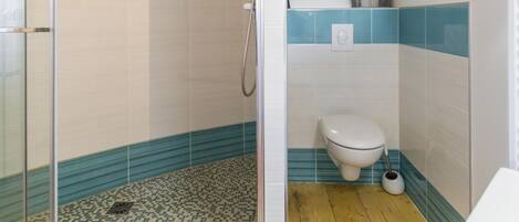 A bathroom with a glass-enclosed shower, a toilet, and a sink.