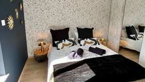 A modern bedroom with a large bed, two bedside tables, a mirror, and a patterned wallpaper. - Spacious lodge in Sanchey near the lake, sauna, games, close to nature (Sanchey)