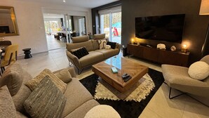 A modern living room with a sofa, armchairs, a coffee table, and a TV. - Spacious lodge in Sanchey near the lake, sauna, games, close to nature (Sanchey)
