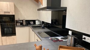 A modern kitchen with a built-in oven, a stovetop, and a sink. - Spacious lodge in Sanchey near the lake, sauna, games, close to nature (Sanchey)