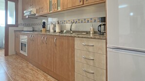 Una cocina moderna con armarios de madera, una campana extractora de acero inoxidable, horno empotrado, cafetera y refrigerador.