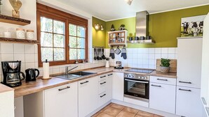 A modern kitchen with white cabinets, a stainless steel stove, and a window with a view of greenery.