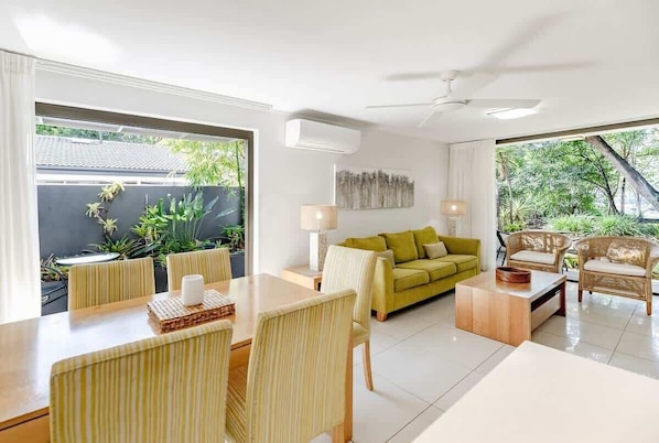 A modern living room with a dining area, a sofa, and a coffee table.