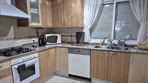 A kitchen with wooden cabinets, a stove, a microwave, a dishwasher, and a window with curtains.