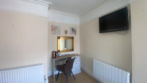 A bedroom with a bed, a desk, a chair, a television, and artwork on the wall. - Stokesay inn and b and b  (Craven Arms)
