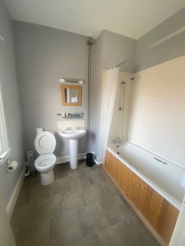 A bathroom with a toilet, sink, and bathtub. - Stokesay inn and b and b  (Craven Arms)