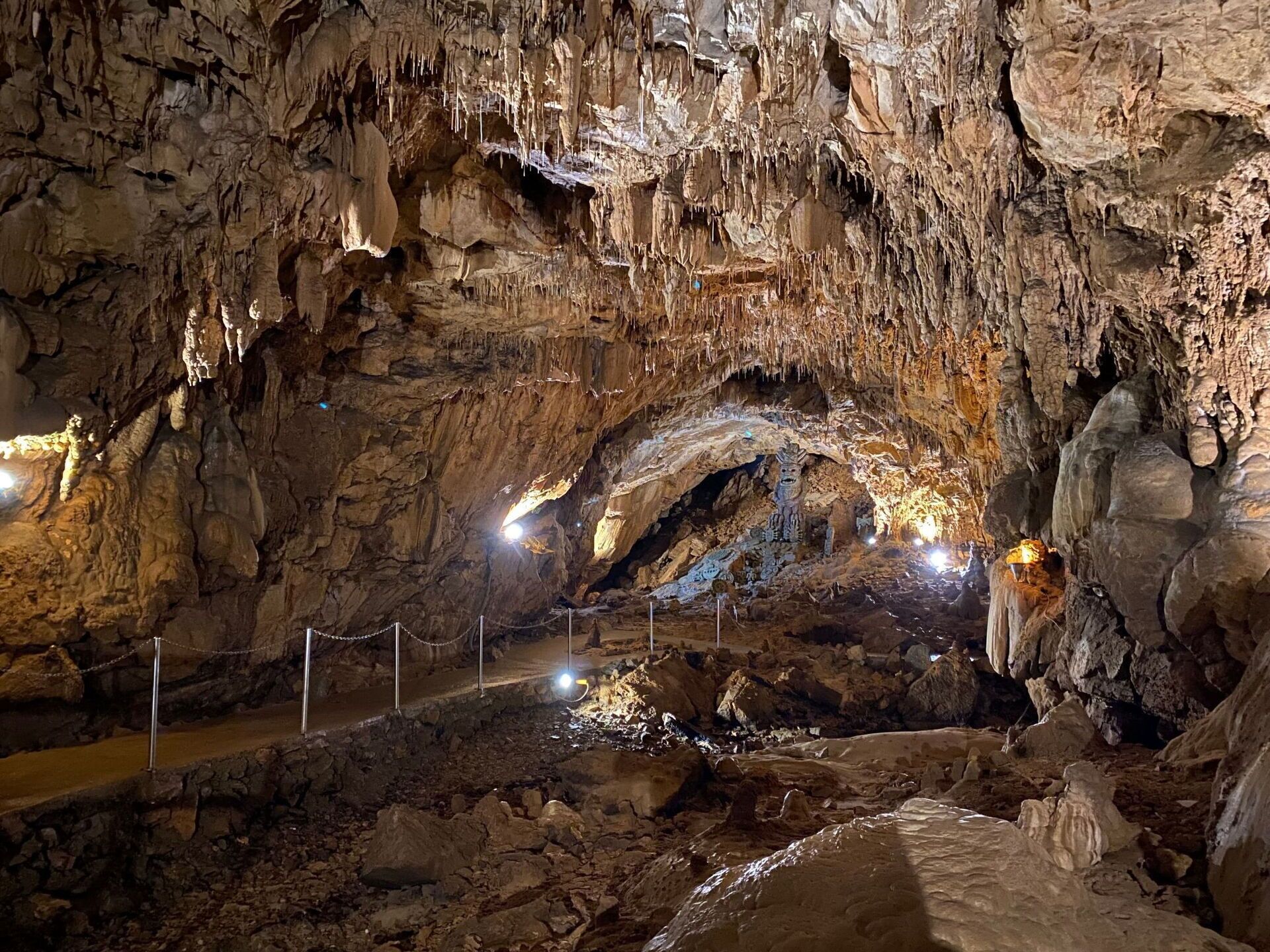 Una cueva con estalactitas y estalagmitas, una barrera de cuerda y una fuente de luz.