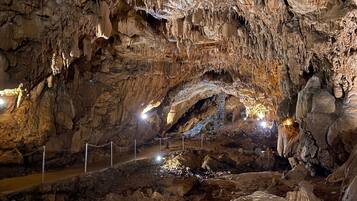 Una cueva con estalactitas y estalagmitas, una barrera de cuerda y una fuente de luz.