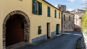 A narrow street with a yellow building featuring a stone archway, green shutters, and a small door. - Cosy apartment for 4 guests with WIFI, A/C, TV and terrace (Chiesa)