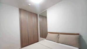 A bedroom with a bed, a wardrobe, and a mirror.
