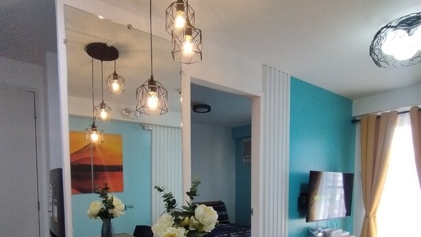 A dining area with a table set for four, a vase with flowers, and a TV on a stand.