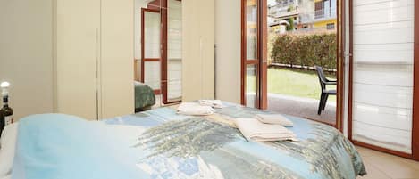 A bedroom with a bed, a wardrobe, and a sliding glass door leading to an outdoor area.