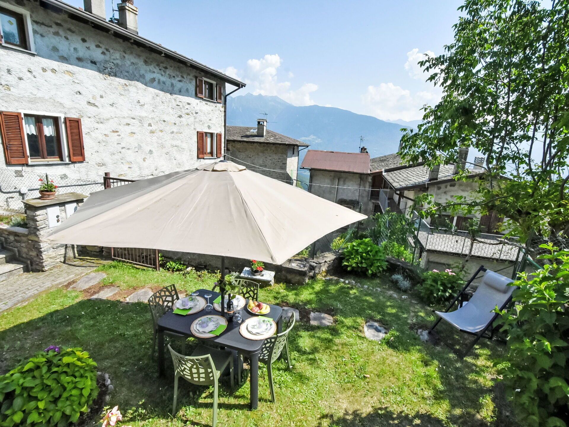 A patio with a table set for a meal, surrounded by stone walls and a view of mountains.