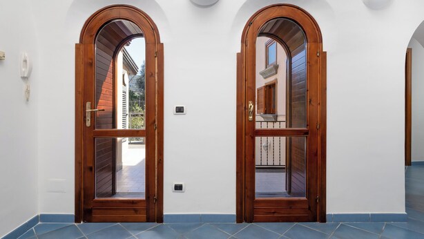 Two wooden doors with glass panels, white walls, and blue-tiled flooring.