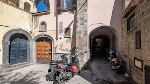 A narrow street with a motorcycle parked in front of a building with a blue door and a stone wall.