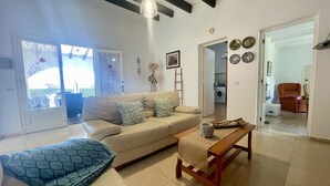 A living room with a sofa, a coffee table, and a bench. There is a door leading to a laundry area.