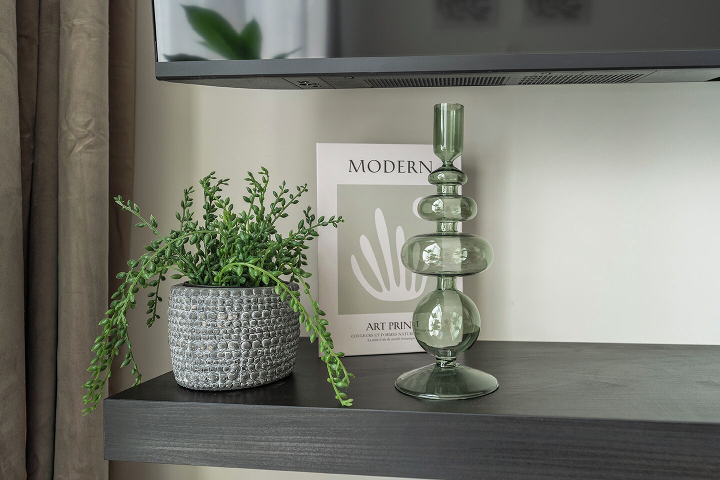 A potted plant and a decorative glass object on a shelf.