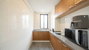 Une cuisine avec des carreaux de céramique blancs disposés en motif métro, des armoires en bois, un four à micro-ondes et un grille-pain.