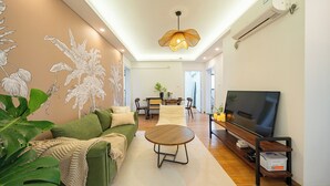 Un salon moderne avec un canapé vert, une table basse ronde et un téléviseur à écran plat.