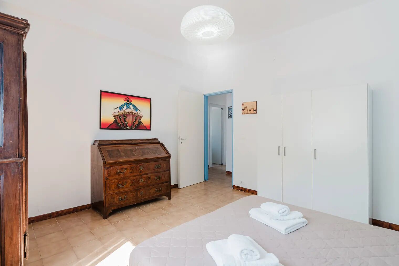 Una habitación de hotel con una cama, un aparador de madera, un cuadro y un armario.