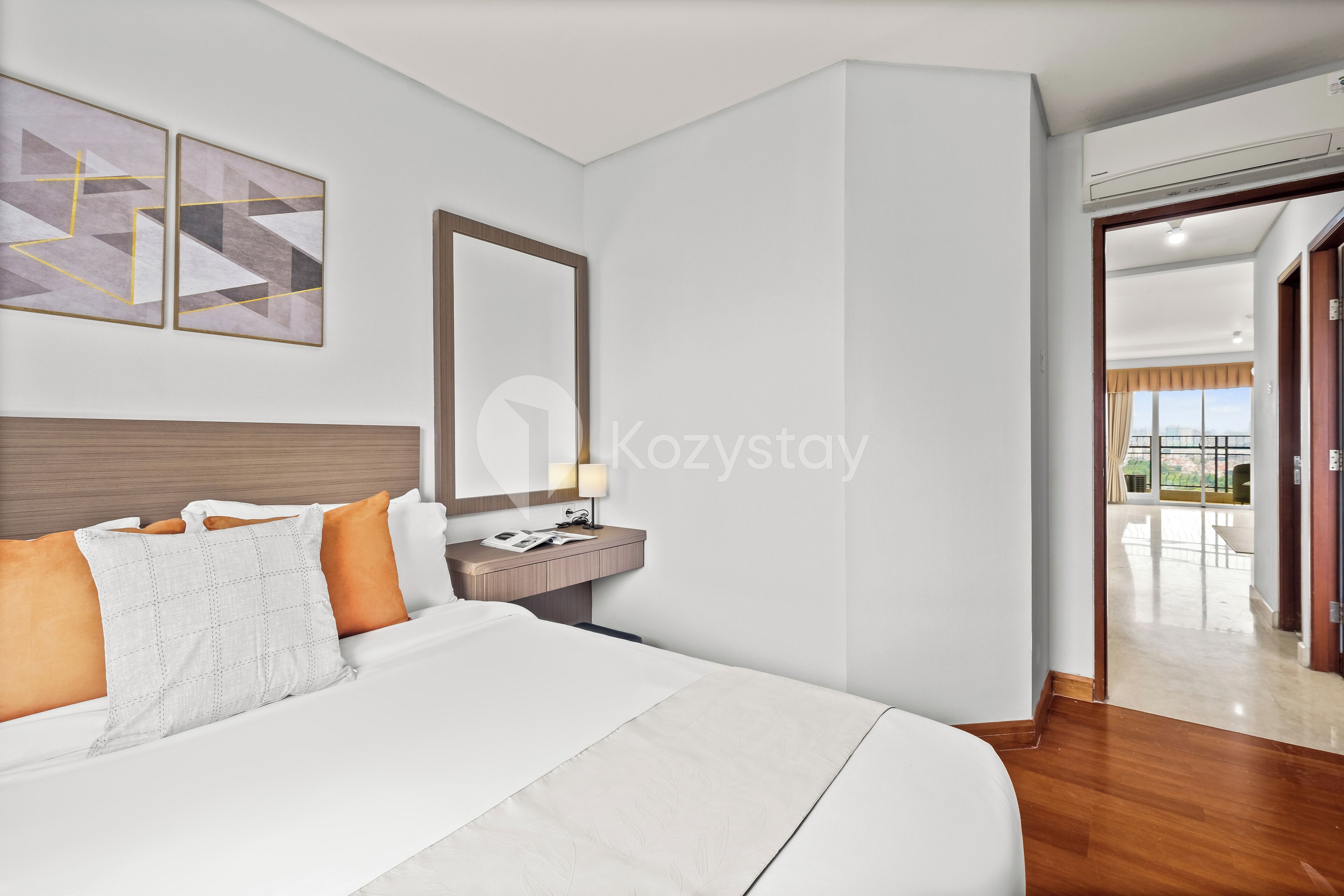 Una habitación de hotel moderna con una cama grande, una mesita de noche con lámpara y vistas al balcón.