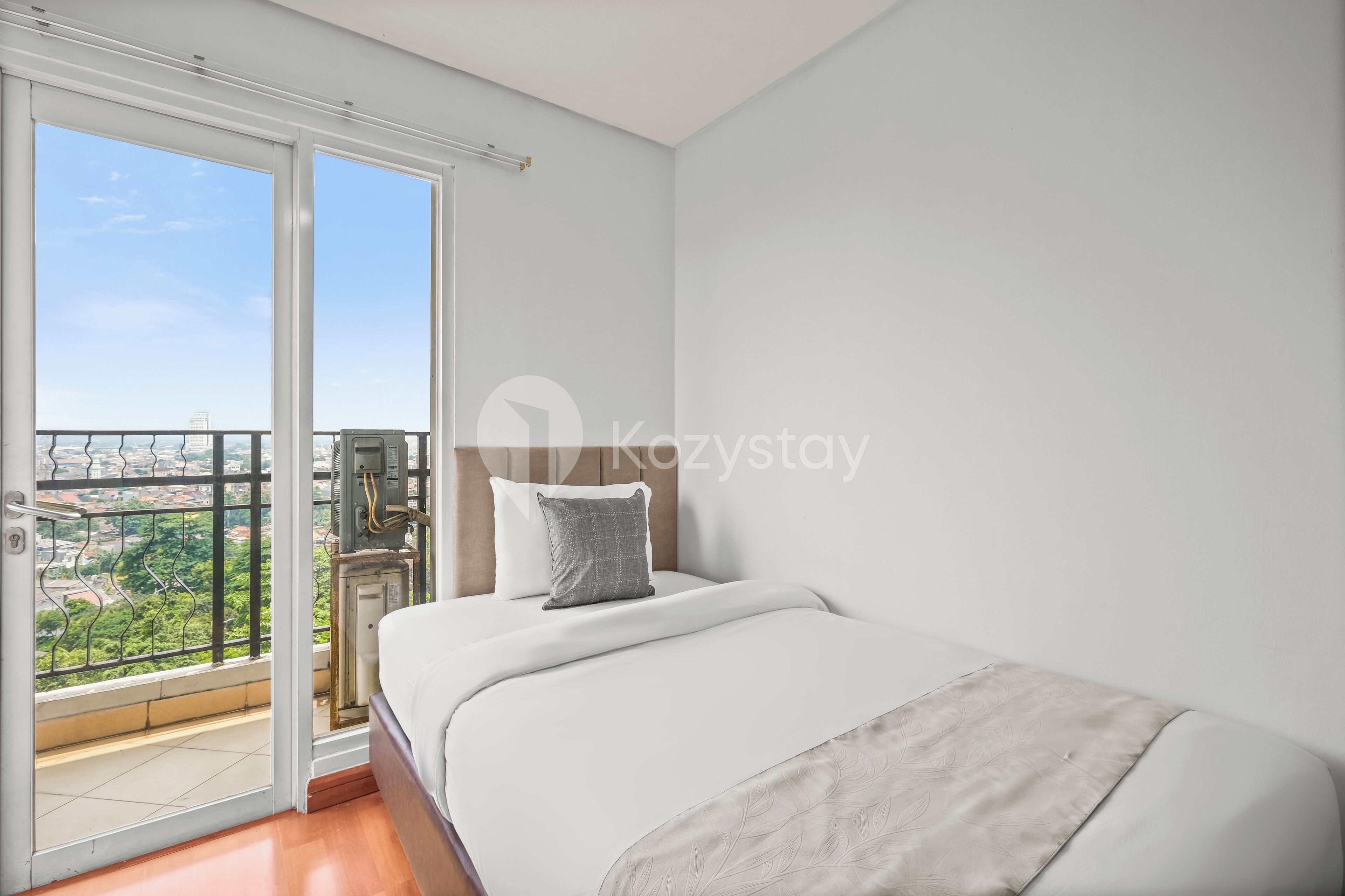 Een slaapkamer met een bed, een raam en uitzicht op een stadsgezicht.
