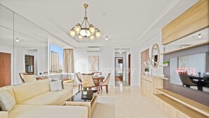 A modern living room with a sofa, dining table, and chairs, a TV, and a chandelier.