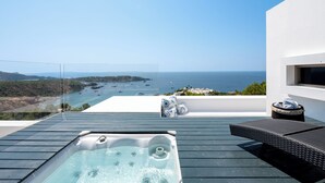 A rooftop with a hot tub, outdoor seating, and a view of the sea.