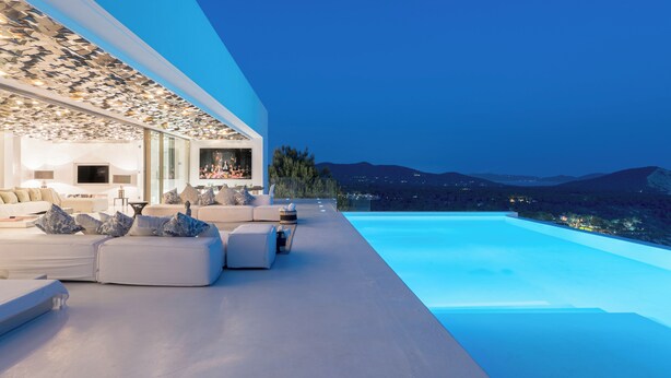 A modern outdoor living area with a pool, seating, and a view of the mountains.