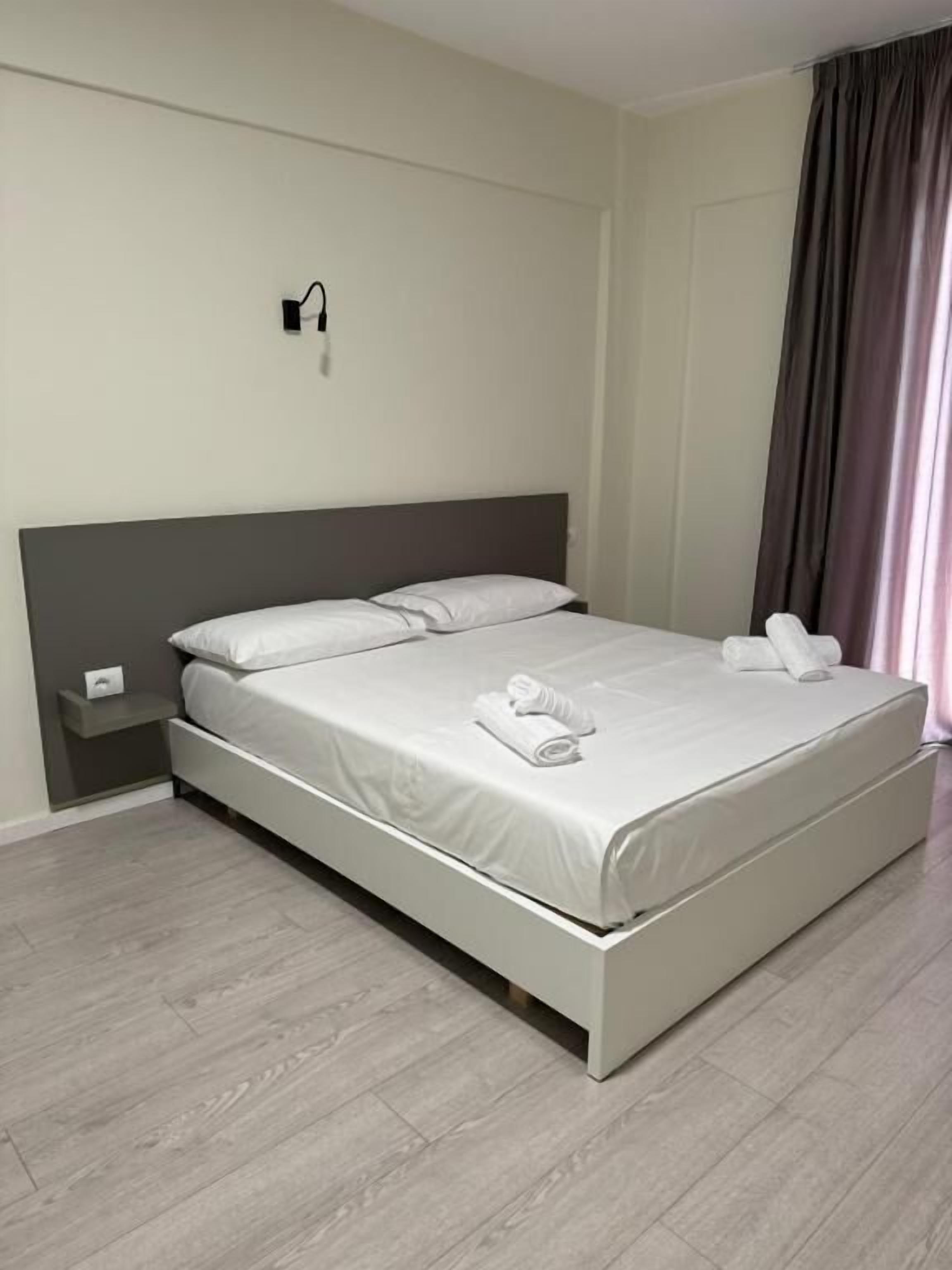 Une chambre moderne avec un grand lit, une table de chevet et une lampe fixée au mur.