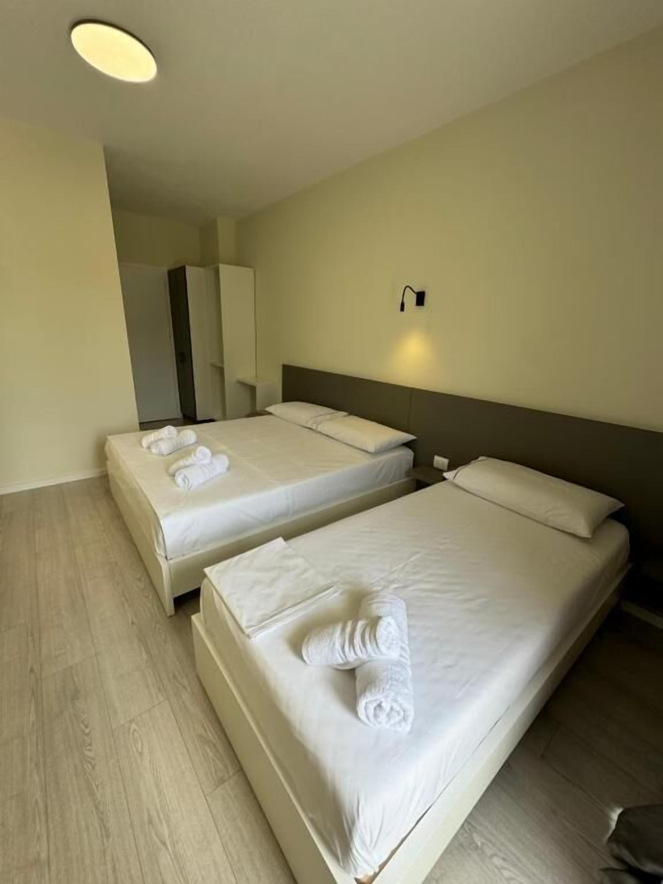 A hotel room with two beds, each with neatly folded towels.