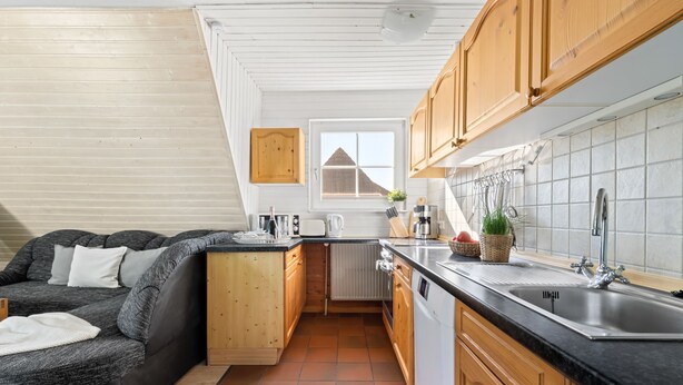 Une cuisine de taille réduite avec des meubles en bois, un plan de travail noir et une fenêtre.