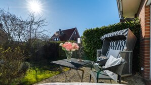 A patio with outdoor furniture, a table, and a vase of flowers.