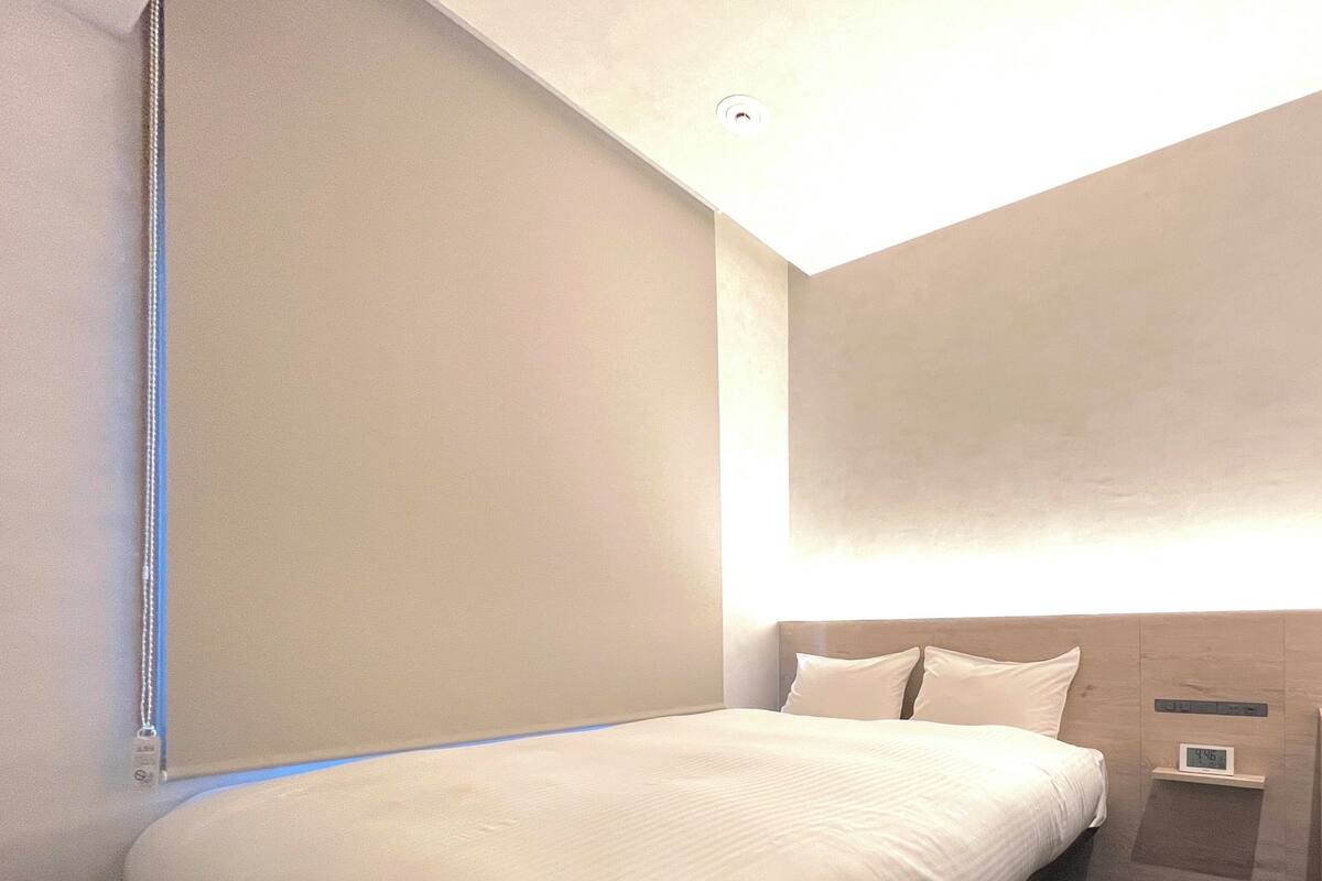 Un lit bien fait, avec du linge de lit blanc, dans une chambre d’hôtel moderne.