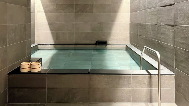 A modern spa room with a rectangular pool, tiled walls, and a built-in bench. - KyotoABizhotel (Kyoto)