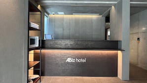 A reception desk with a sign reading "ABiz hotel" in a modern lobby with concrete walls and a tiled floor. - KyotoABizhotel (Kyoto)