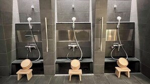 A modern bathroom with three separate shower stalls, each equipped with a handheld showerhead and a wooden stool. - KyotoABizhotel (Kyoto)