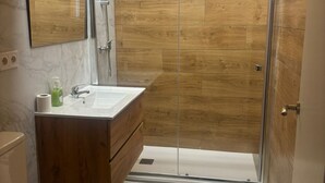 A modern bathroom with a wooden vanity, a glass shower enclosure, and a marble-tiled floor. - SANTA ANA - SEASONAL RENTAL (Alicante (Alacant))