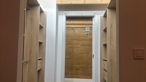 A narrow hallway with wooden shelving on both sides, leading to a door with a small vent. - SANTA ANA - SEASONAL RENTAL (Alicante (Alacant))