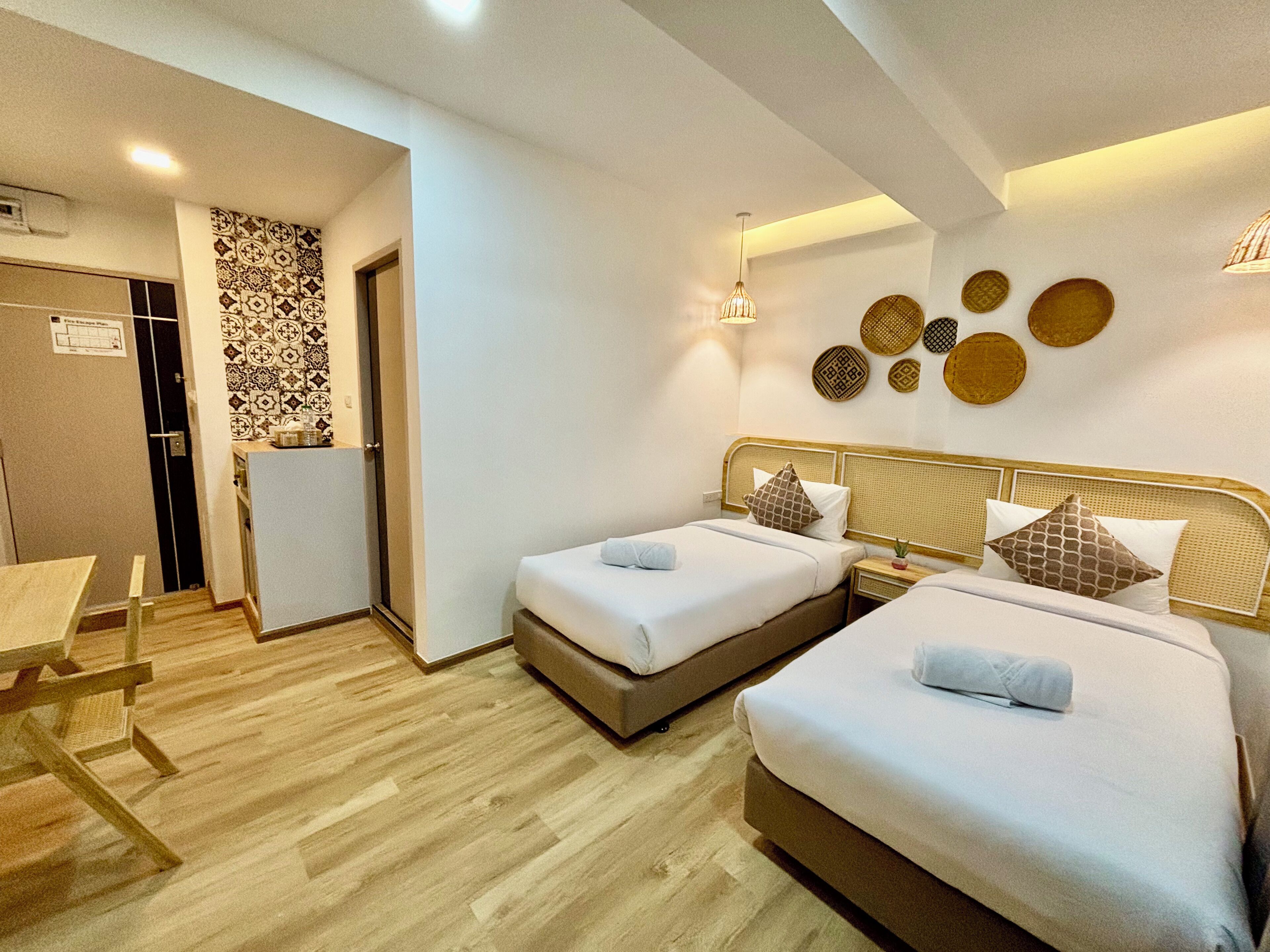 Een hotelkamer met twee bedden, een eettafeltje, een koelkast en een behang met patroon.