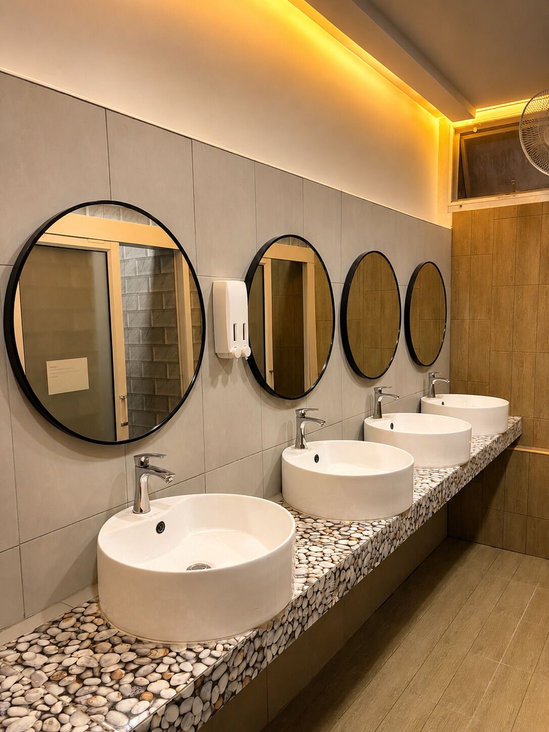 A bathroom with three sinks, each with a round mirror above.