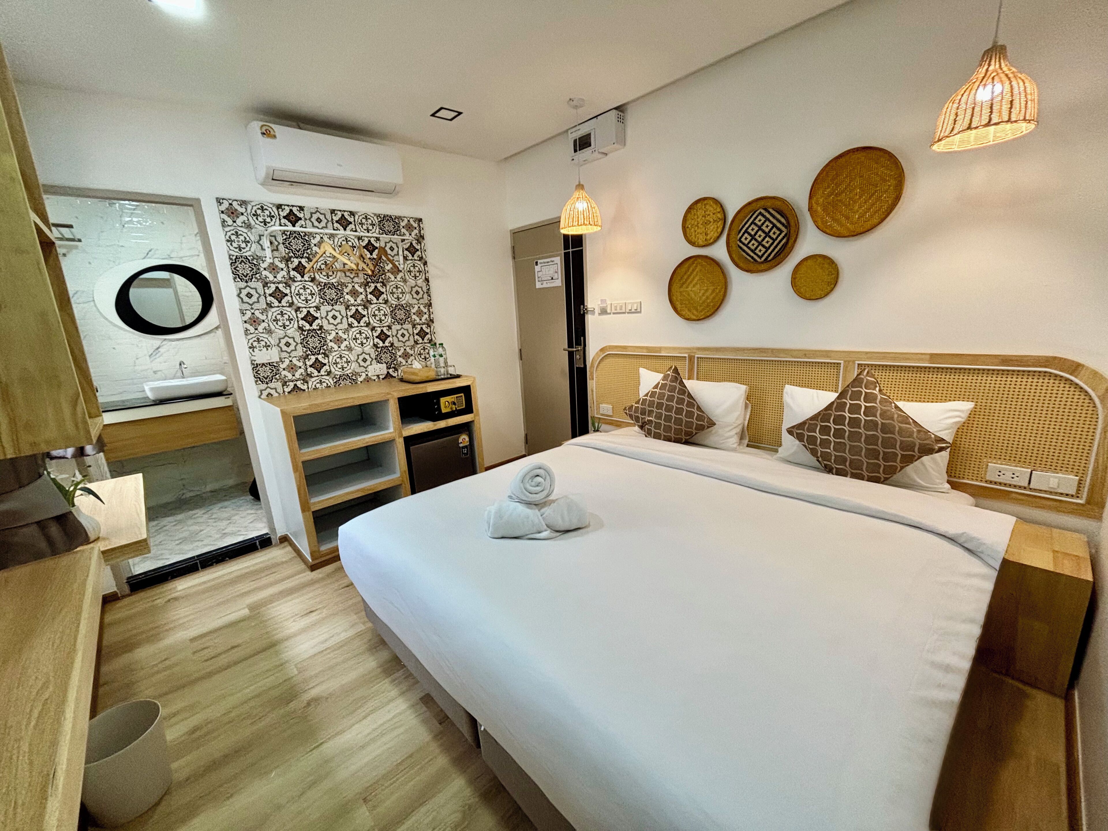 Ein Hotelzimmer mit Bett, Nachttisch und Wandklimaanlage.