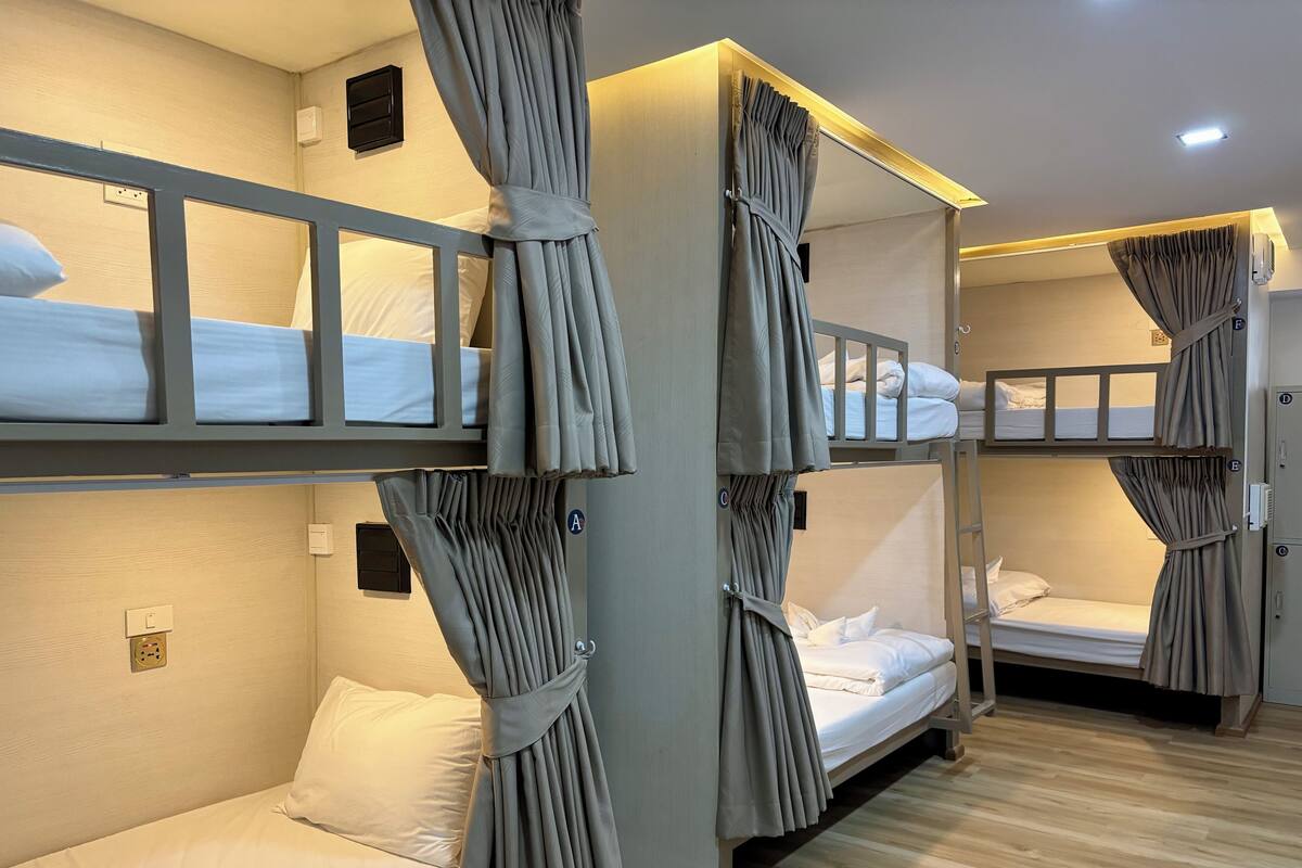 Una habitación con literas, cortinas grises y suelo de madera.