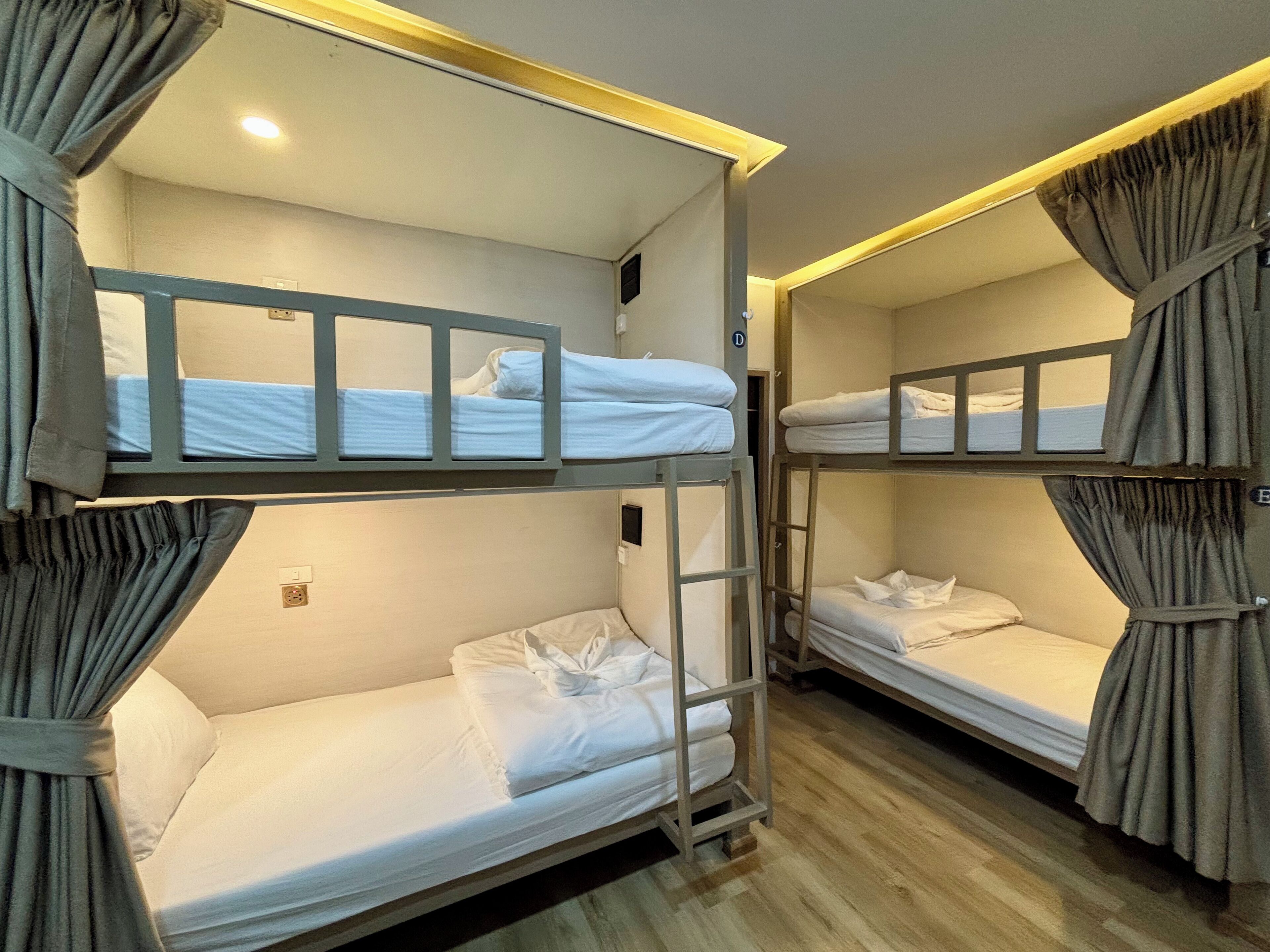 Een slaapkamer met stapelbedden, elk met hoofdeinde en gordijnen.